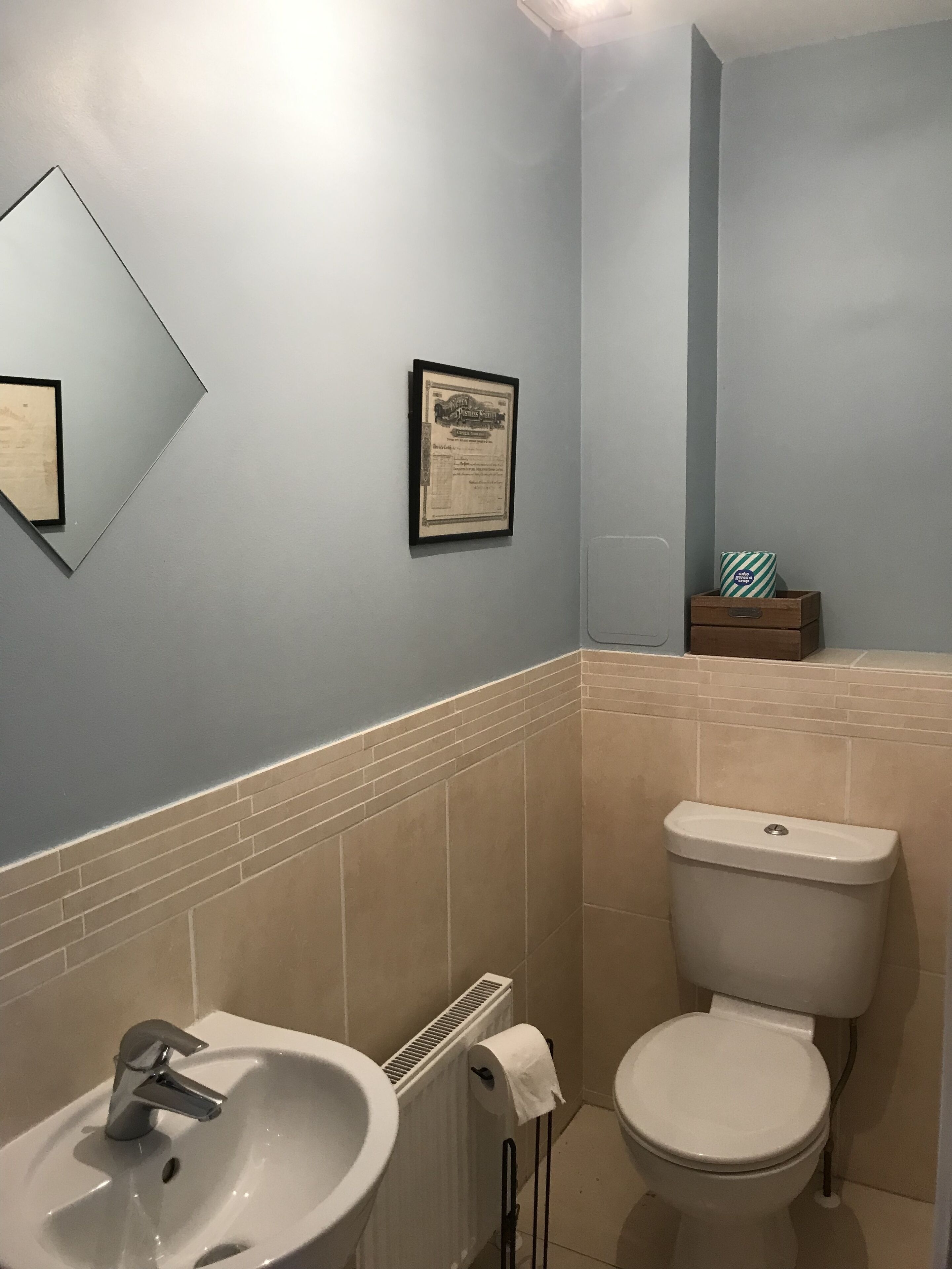 Een badkamer met een wastafel, toilet en een gecertificeerde lijst aan de muur.