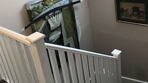 Una escalera con barandilla blanca, tragaluz y aplique de pared.