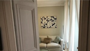 Vista del interior de una habitación con un sofá color beige, una mesa de centro redonda y una alfombra blanca.