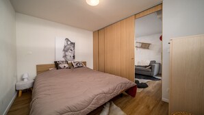 Ein Schlafzimmer mit einem Bett, einem Holzschrank, einem grauen Sofa und einem gerahmten Bild an der Wand.