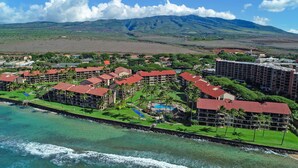 A coastal resort with multiple buildings, a swimming pool, and a view of mountains.