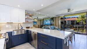 A modern kitchen with dark blue cabinets, a stainless steel sink, and a large island with a white countertop.