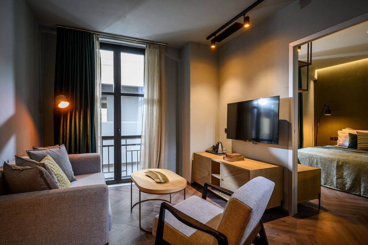 Una habitación de hotel moderna con sofá, escritorio, televisor y cama.