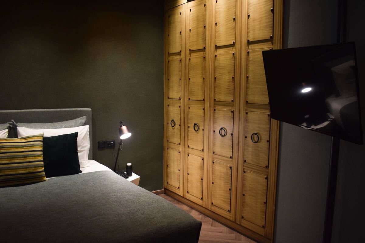 Un dormitorio con cama, televisión, armario y mesita de noche.