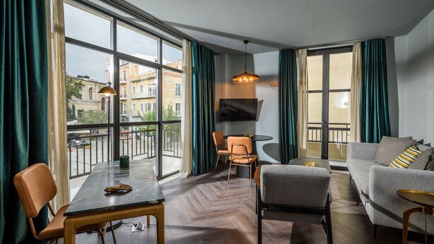 Una sala de estar moderna con comedor, ventanas amplias y vistas a edificios.