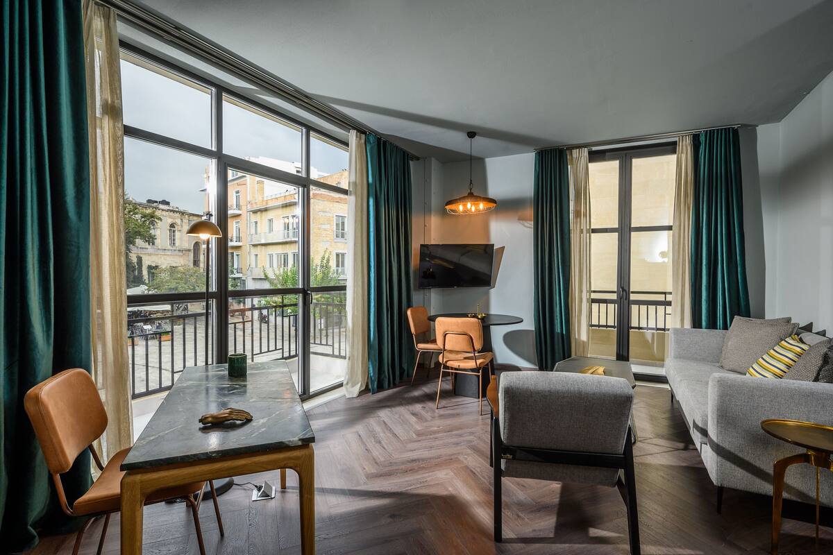 Una sala de estar moderna con comedor, ventanas amplias y vistas a edificios.