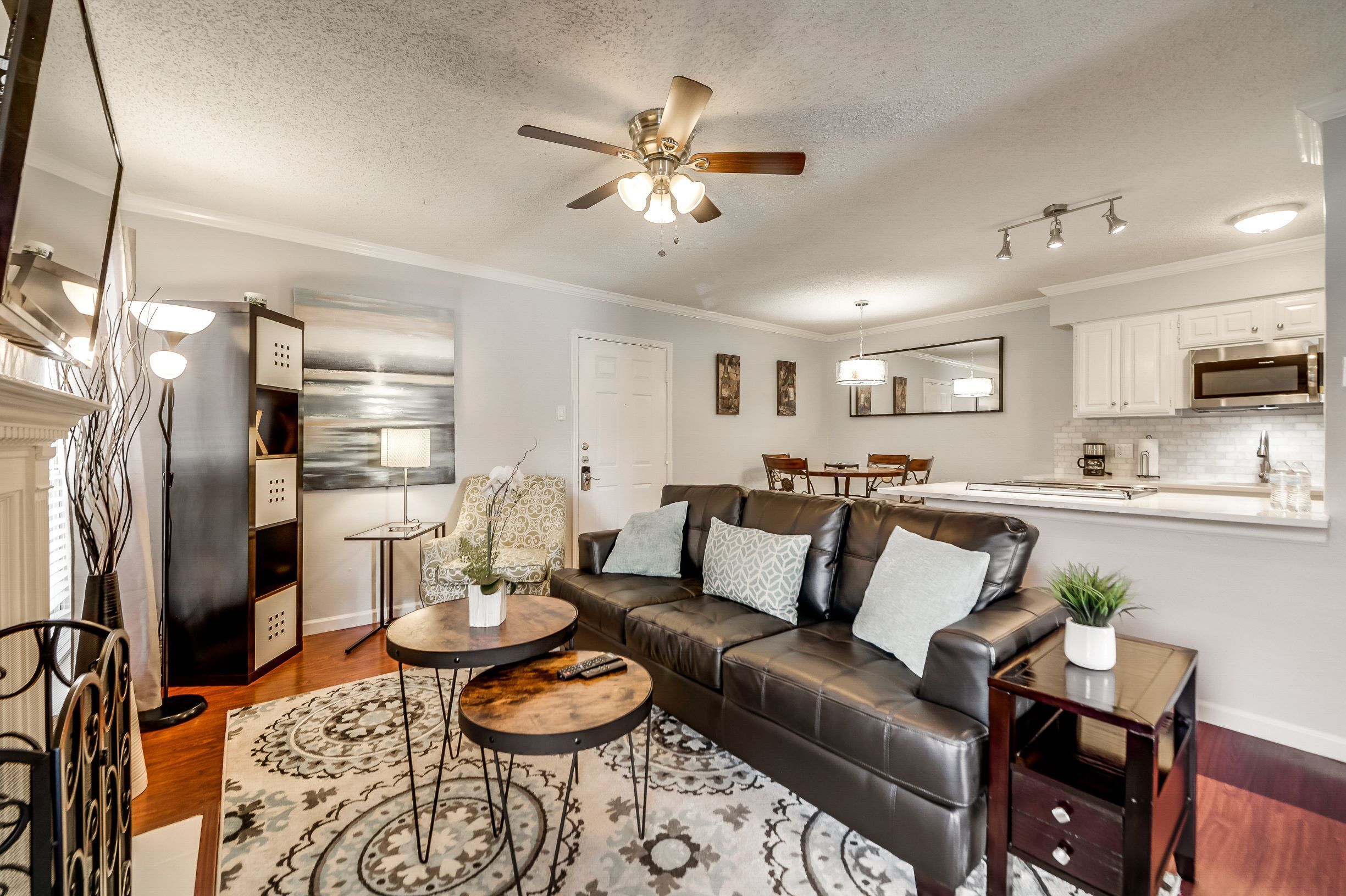 A modern living room with a leather sofa, a coffee table, and a ceiling fan.