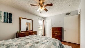 Un dormitorio con cama, cómoda, espejo y ventilador de techo.