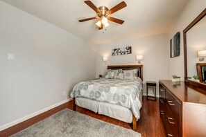 A bedroom with a bed, a ceiling fan, a nightstand, a dresser, and a mirror.