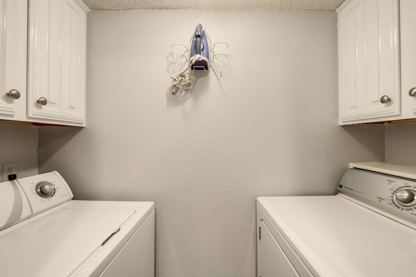 A laundry room with two white washing machines and a wall-mounted dryer.