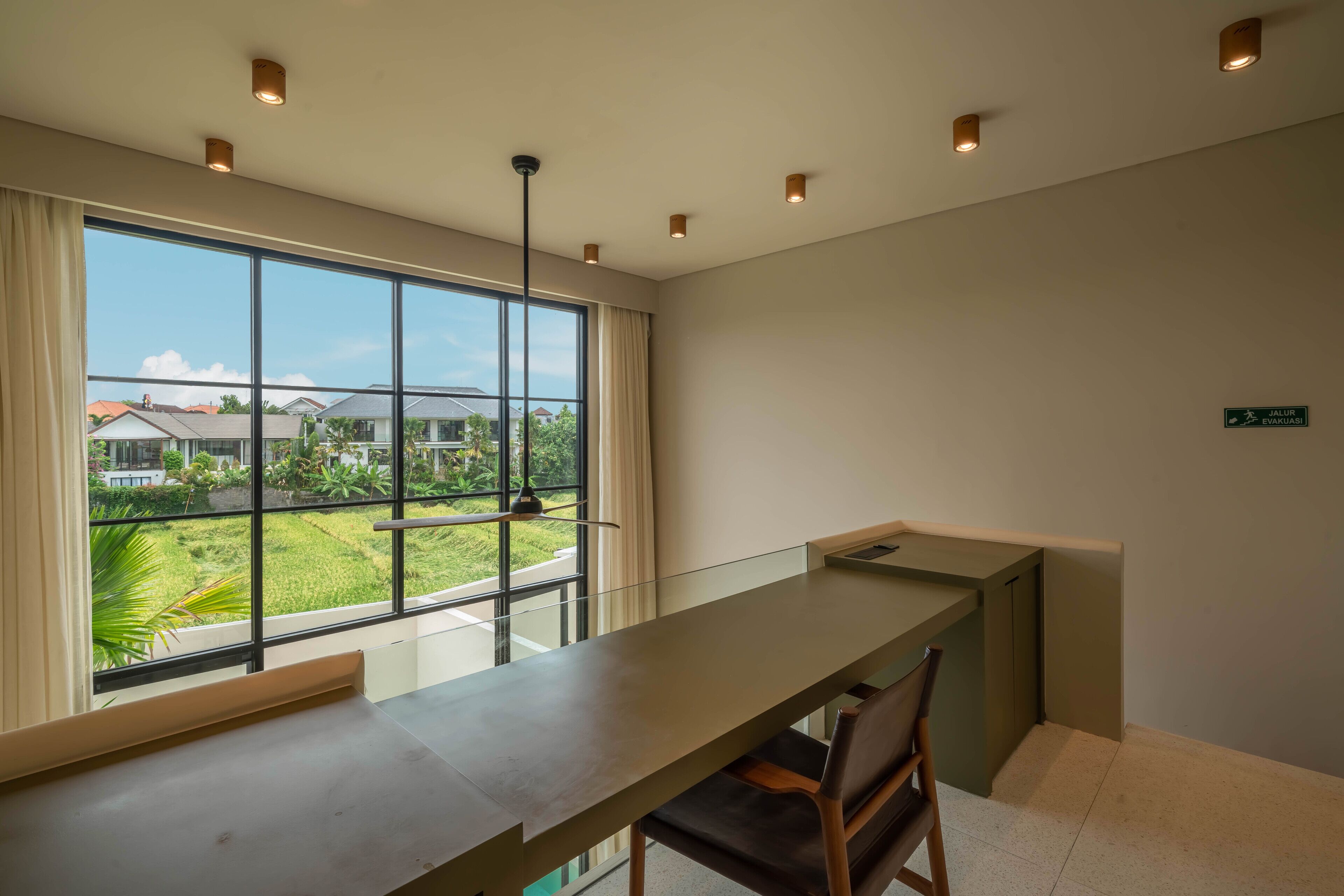 Una habitación moderna con un ventanal grande, una mesa larga y una silla.