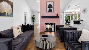 Una sala de estar moderna con chimenea, sofás oscuros y una mesa de centro redonda.