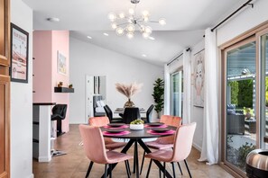 Uma sala de jantar moderna com uma mesa redonda, cadeiras cor-de-rosa e um candelabro.