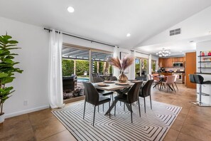A spacious dining area with a large table, chairs, and a view of a pool. - Palm Springs Paradise (Palm Springs)