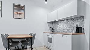 A modern kitchen with white cabinets, a patterned backsplash, and a wooden countertop. - RentPlanet - Apartament Muranów (Warsaw)