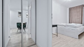A modern bedroom with a bed, a desk, and a chair. - RentPlanet - Apartament Muranów (Warsaw)