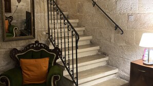 A staircase with a wrought iron railing, a green armchair with an orange cushion, and a small table with a lamp. - Charming Central Townhouse in Sliema  (Sliema)