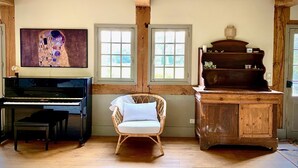 Une pièce comprenant un piano à queue, un fauteuil en osier et un meuble en bois.