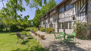 Un bâtiment traditionnel à colombages doté d’une terrasse en gravier, de sièges d’extérieur et de plantes en pot.