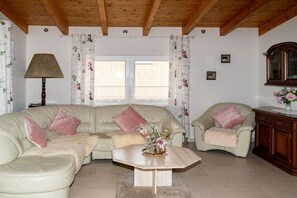 Un salon avec un canapé beige, une table basse en bois, une lampe et un fauteuil.
