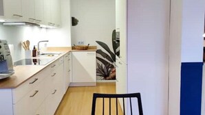 Eine moderne Küche mit weißen Schränken, einer Holz Arbeitsplatte und einem schwarzen Stuhl.