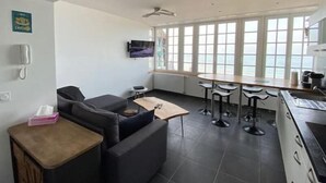 Eine moderne Küche mit Essbereich, großen Fenstern und einem Flachbildfernseher.