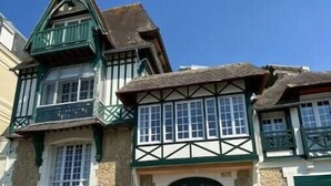 Ein traditionelles Gebäude im Tudor-Stil mit einem steilen Satteldach, grünen Akzenten und einer symmetrischen Fassade.