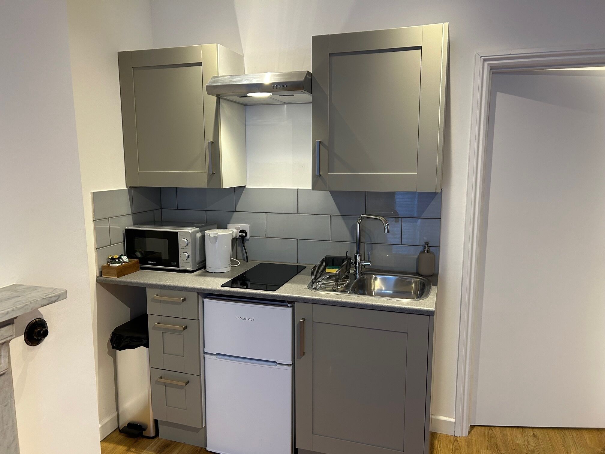 A compact kitchen with a microwave, toaster, sink, and a small refrigerator.