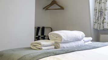 A neatly made bed with rolled white towels and a grey blanket.