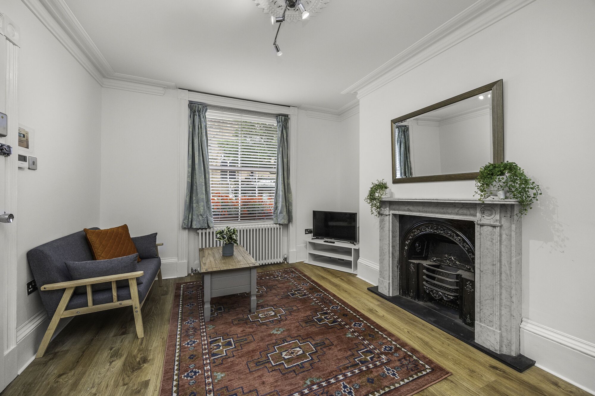 A living room with a fireplace, a television, a sofa, and a patterned rug.