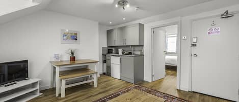 A compact living space with a kitchenette, a dining area, and a TV.