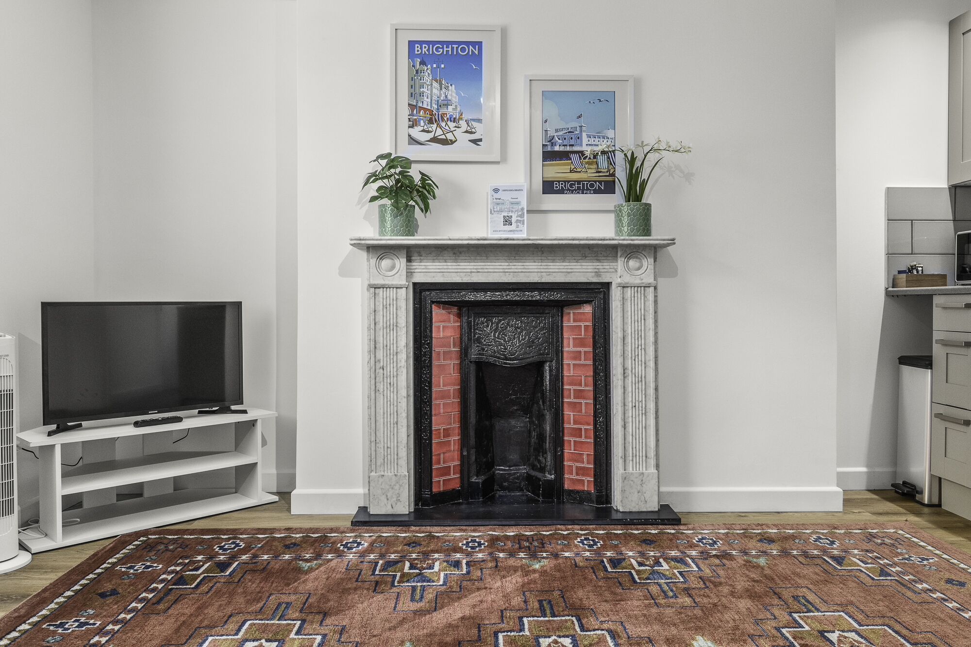 A living room with a fireplace, a television, and a patterned rug.