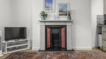 Un salón con chimenea, televisor y una alfombra estampada.