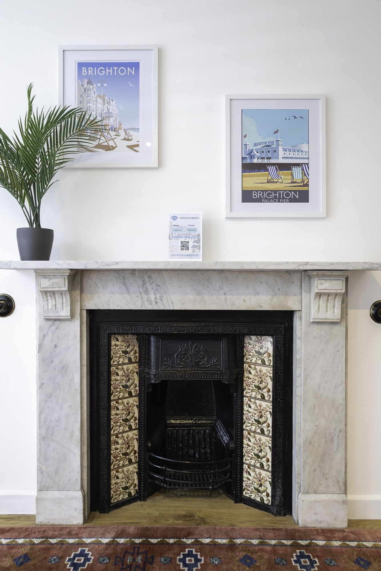 A fireplace with a decorative screen, a framed picture of Brighton Palace Pier, and a framed picture of Brighton.