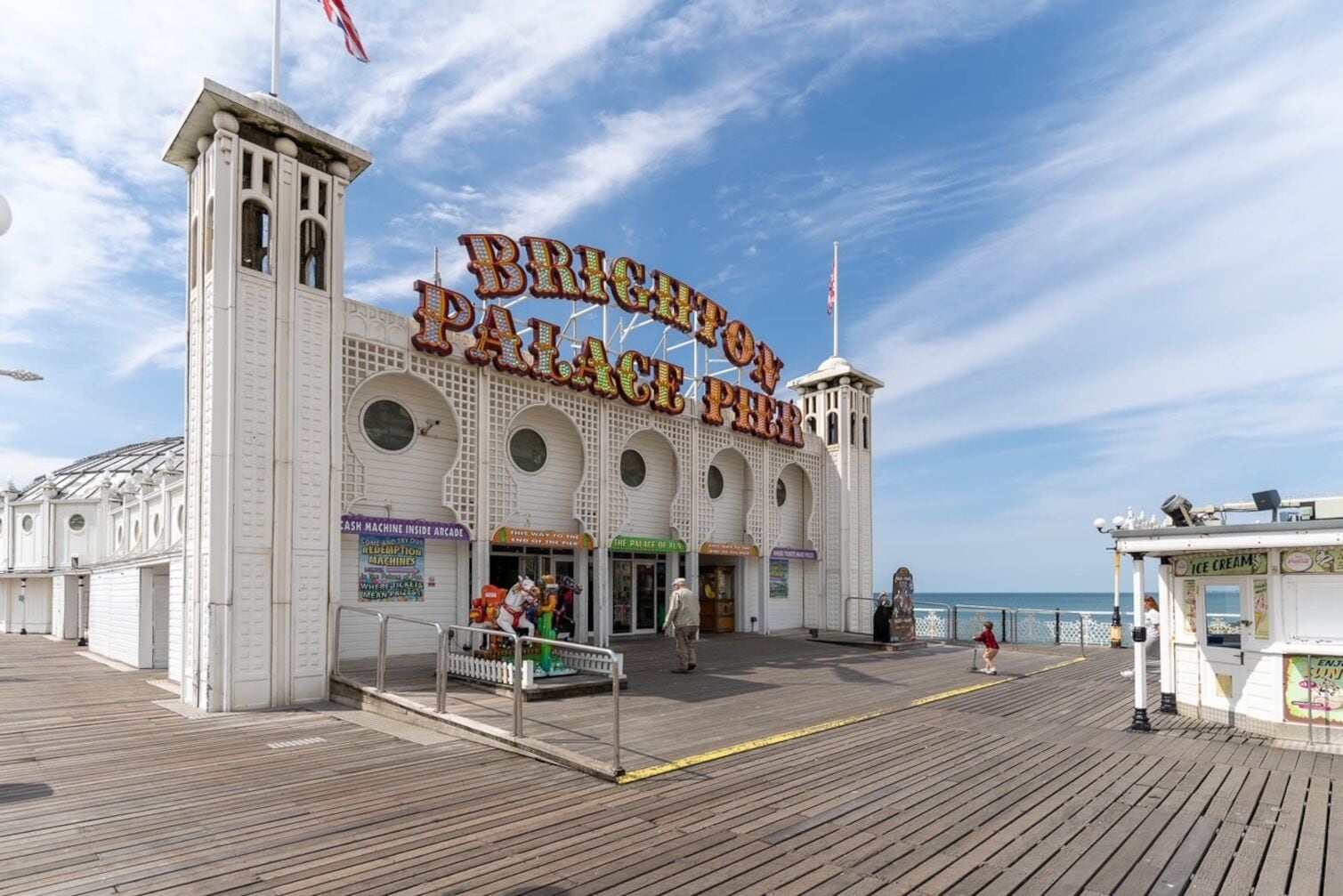A seaside boardwalk with a prominent building labeled "Brighton Palace Pier."
