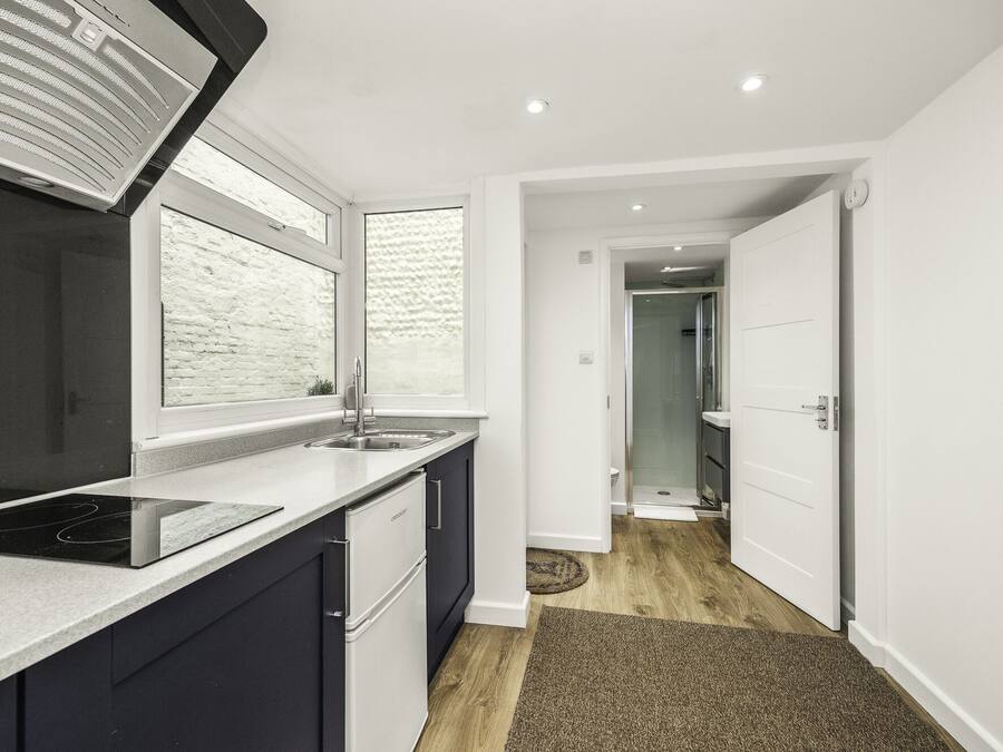 A modern kitchen with a built-in stove, a sink, and a window with a white brick wall.