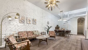 Un salon moderne avec un mur en briques blanches, un plancher en bois et un escalier menant à un niveau supérieur.