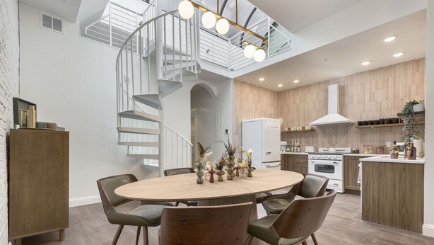 Une cuisine moderne dotée d’un îlot central, d’un coin repas avec une table ronde et des chaises, et d’un escalier en colimaçon.