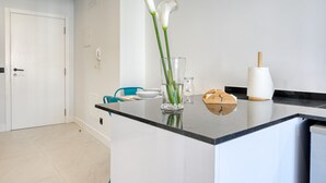 A modern kitchen with a black countertop, a white door, and a vase with white flowers. - Beco Santa Emilia 4P, a Home in Madeira (Funchal)