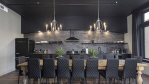 A modern kitchen with a marble backsplash, black cabinetry, and pendant lighting. - Penthouse Grand Executive Suite (Louisville)