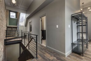 Ein modernes Interieur mit einer Treppe, einer Metallregaleinheit und Blick ins Freie durch ein Fenster.