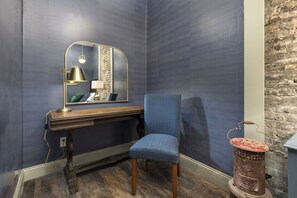 Ein Zimmer mit blauer Wand mit Struktur, einem Holztisch mit Lampe, einem blauen Stuhl und einem alten Herd.