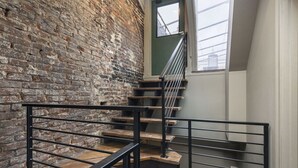 A staircase with wooden steps and black metal railings, leading to a door with a window above it. - Penthouse Grand Executive Suite (Louisville)