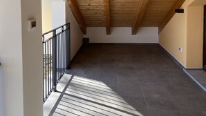 Un espace mansardé avec un plafond en bois incliné et un balcon doté d’une rambarde en métal.