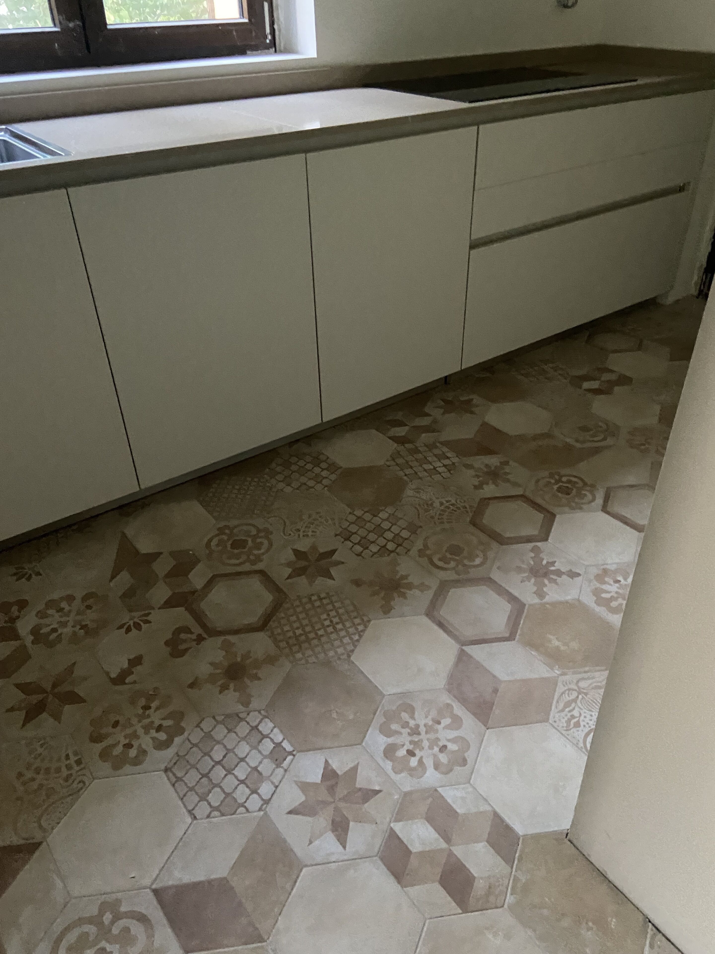 A kitchen with a tiled backsplash and a patterned floor.
