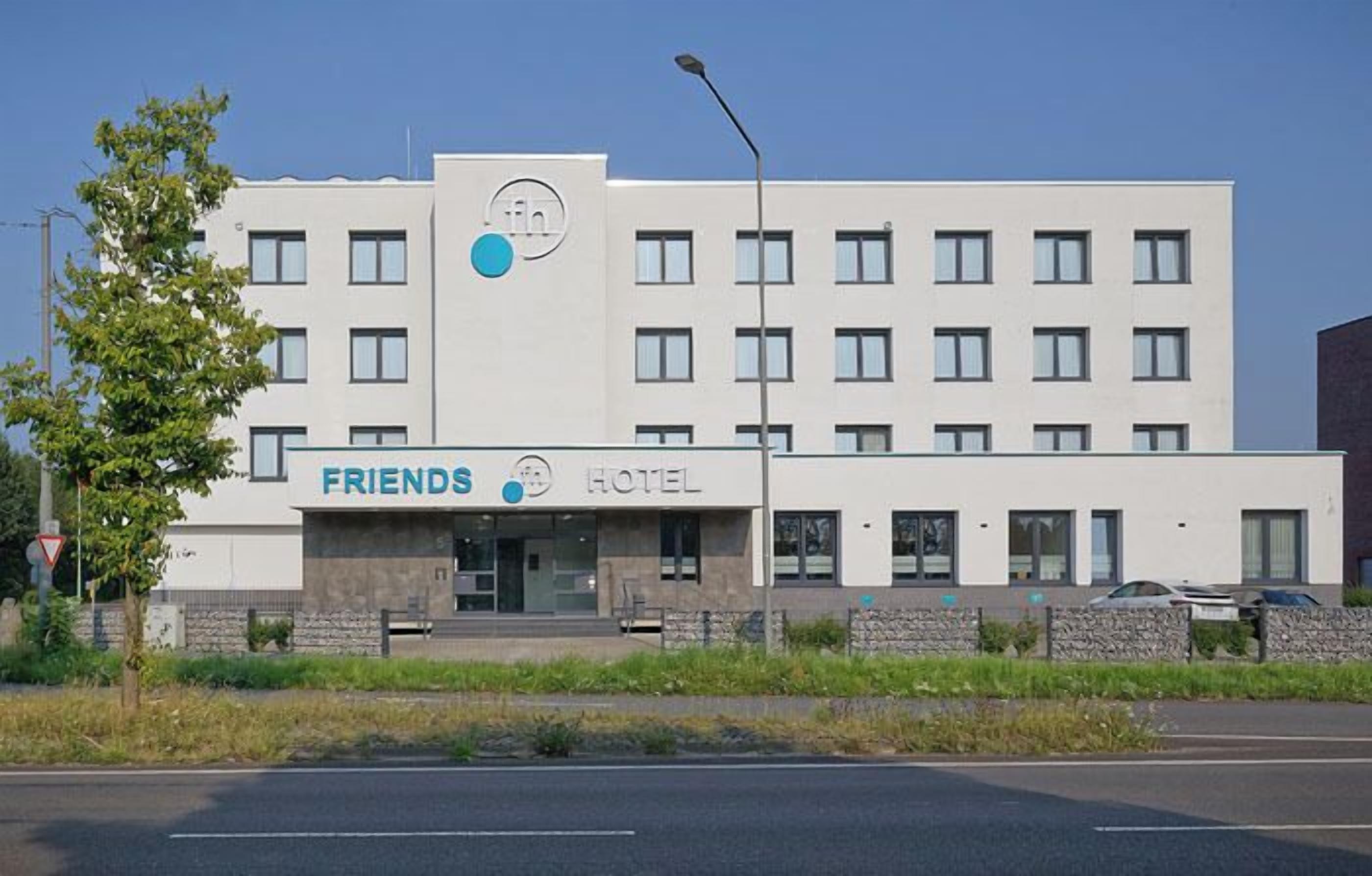 UN HÔTEL À L’ENSEIGNE « FRIENDS », doté d’une façade moderne, de nombreuses fenêtres et d’un logo bien visible.