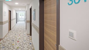 Een hotelgang met een vloer met geometrisch patroon, houten deuren en een bordje met kamer 301.