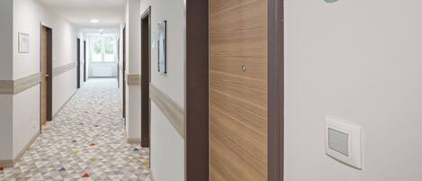 A hotel corridor with a geometric patterned floor, wooden doors, and a number sign indicating room 301.