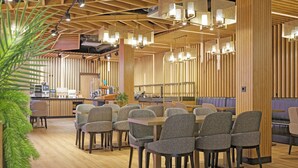 Een modern restaurant met houten lambrisering, een bar en verschillende zithoeken.