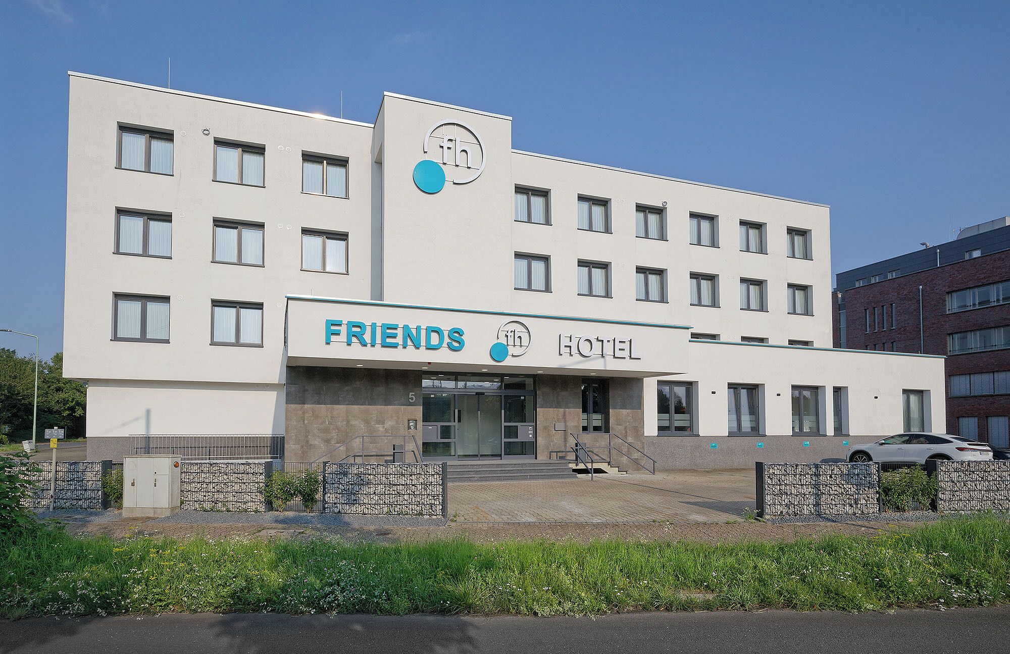 A modern hotel with a flat facade, multiple windows, and a sign reading "FRIENDS HOTEL".
